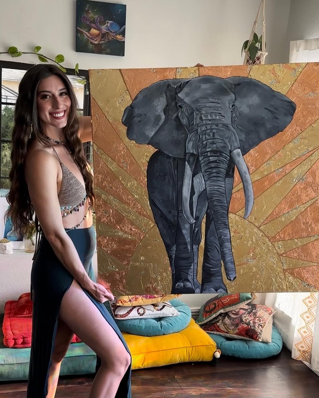 Taylor Christine standing beside her gold elephant painting in her studio